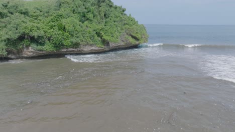drone aéreo de baja altitud disparado sobre aguas residuales contaminadas fangosas y basura flotante con escombros sobre arrecife de coral muerto mezclándose con agua turquesa y costa tropical en bali indonesia