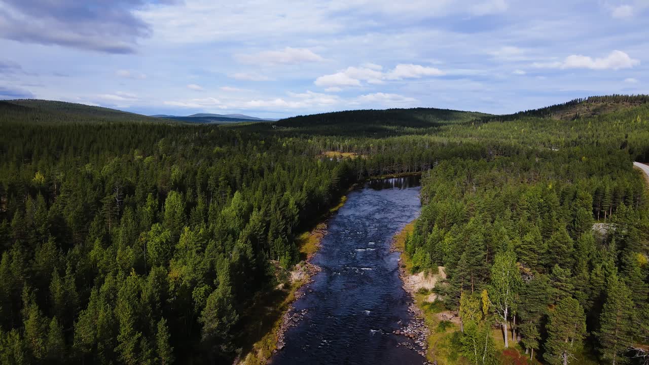 Sjön Inarinjärvi som sträcker sig genom skog med en motorväg längs med, Inari, Finland.
