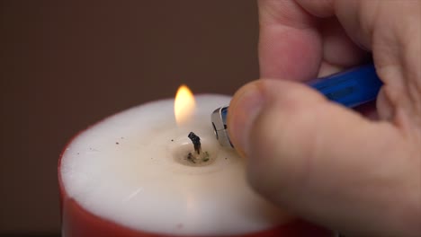 Male-hand-lighting-candle-carefully-with-lighter-flame