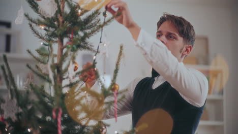 man placing fairy lights on christmas tree at home