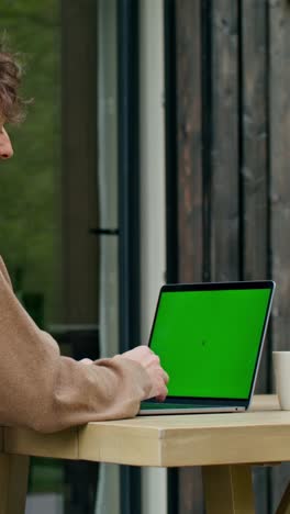 hombre trabajando desde casa en una computadora portátil con pantalla verde