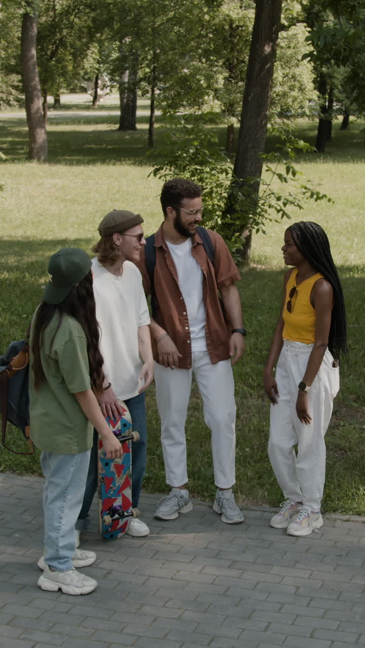 Mangfoldig gruppe unge venner, der har en livlig samtale i en solrig park.
