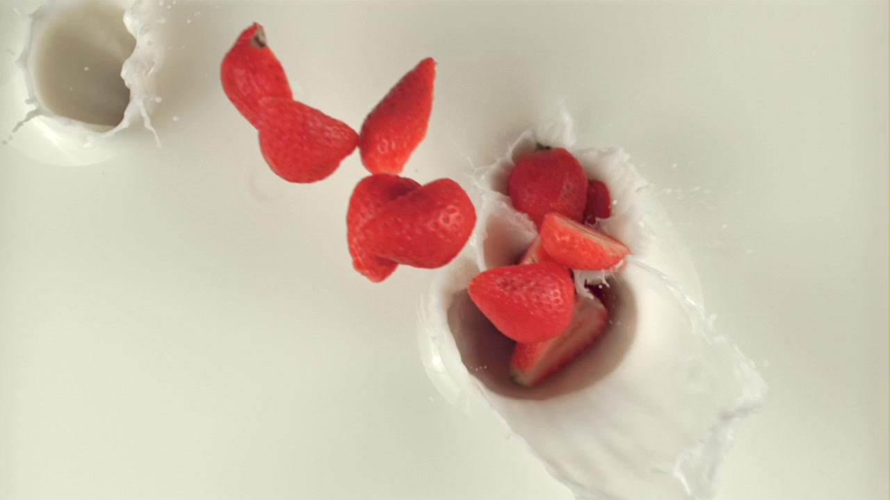 Fresh Red Strawberries Splashing into White Milk in Slow Motion