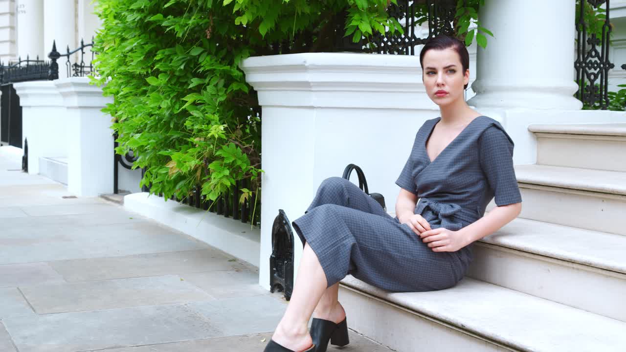 joven consciente de la moda sentada en los escalones del edificio de la ciudad
