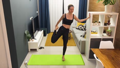 mujer practicando la postura de equilibrio de yoga en casa