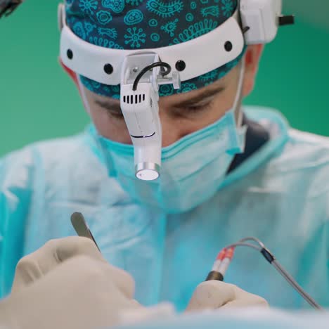 portrait of microsurgeon man. doctor in mask and in special medical clothes in the operating room. surgeon makes an operation. hospital equipment.