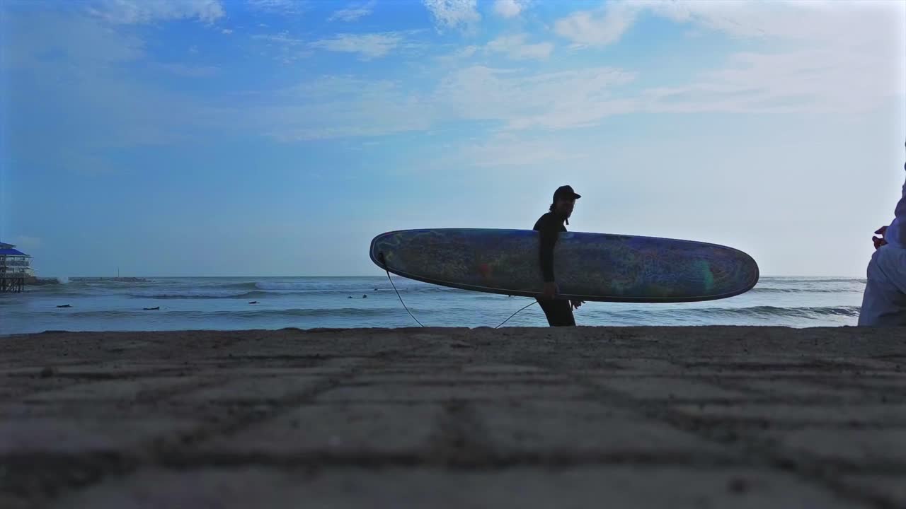 Longboard-Surfer geht auf Kieselsteinen, große Dünungswellen brechen, Miraflores Playa Makaha Beach, Luftaufnahme mit Drohne, Lima Peru Barranquito Gehweg, Sonnenuntergang, goldene Stunde, Dunst, Wolken, Menschenmassen, Surfschule, statische Aufnahme