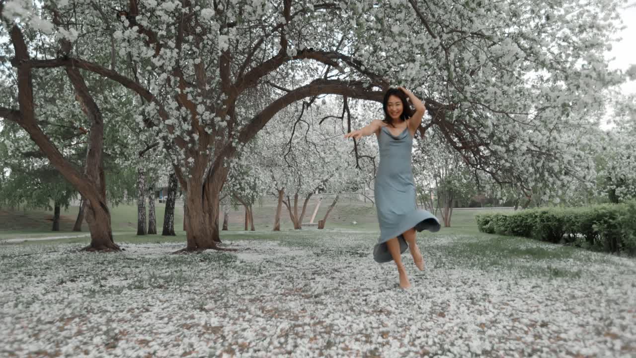 Woman Walking Through a Spring Blossom-Covered Park