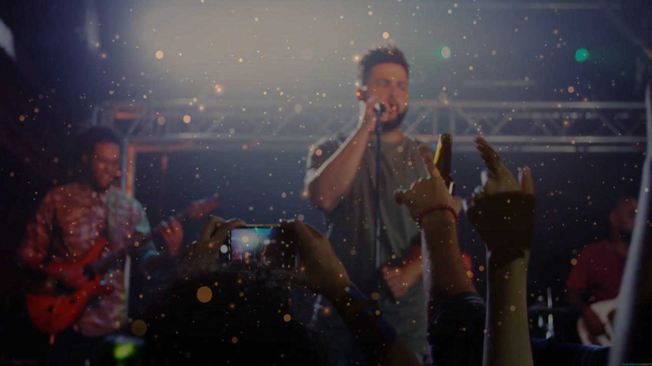 Band che si esibisce con il cantante solista uomo che canta al microfono in un club, incitando la folla a sollevare i telefoni per registrare.