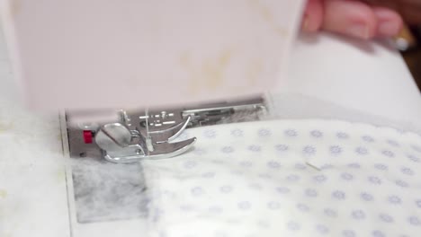 a presser foot of a sewing machine used by a seamstress in making facemasks at home during coronavirus outbreak - closeup shot