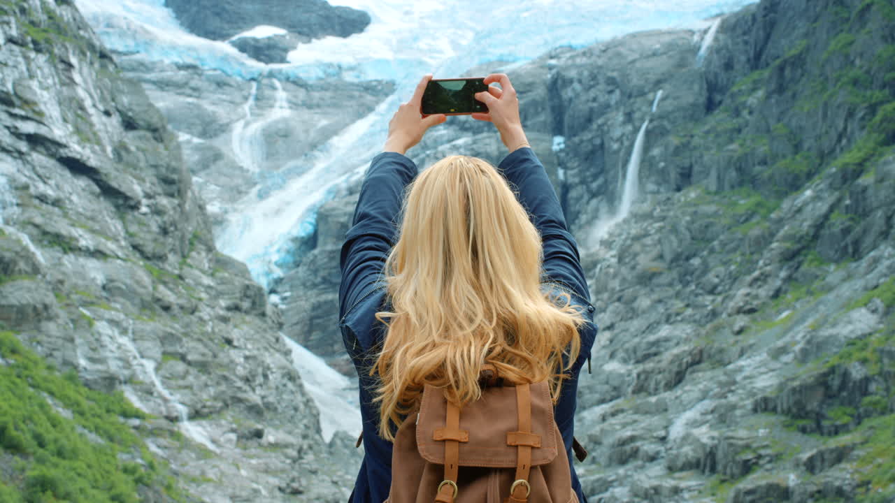 frau, die ein foto von gletscherwasserfällen macht
