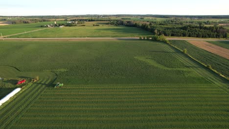 In-Door-County,-WI,-a-farmer-on-a-John-Deere-tractor,-cuts-his-alfalfa-field-in-late-August-18