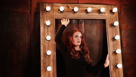 woman in a black dress in front of a vintage mirror with lights