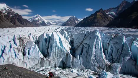 witness adventurers trekking near an expansive glacier surrounded by towering mountains under a clear blue sky. the incredible ice formations and breathtaking scenery captivate all.