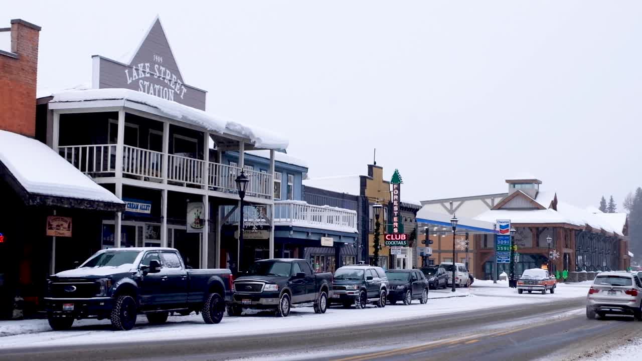 Traffic driving through idyllic town with old fashioned looking shops and buildings covered in snow during the Christmas festive season in McCall, Idaho USA