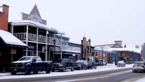 traffic driving through idyllic town with old fashioned looking shops and buildings covered in snow during the christmas festive season in mccall, idaho usa