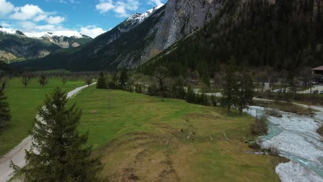 Aerial-4K-flight-at-beautiful-Ahornboden-mountain-valley-along-the-Rissach-river-with-fresh-blue-water-in-the-Bavarian-Austrian-alps-on-a-cloudy-and-sunny-day-along-trees,-rocks,-forest-and-hills