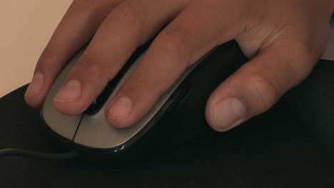 child's hand moving a computer mouse on top of a black mouse pad