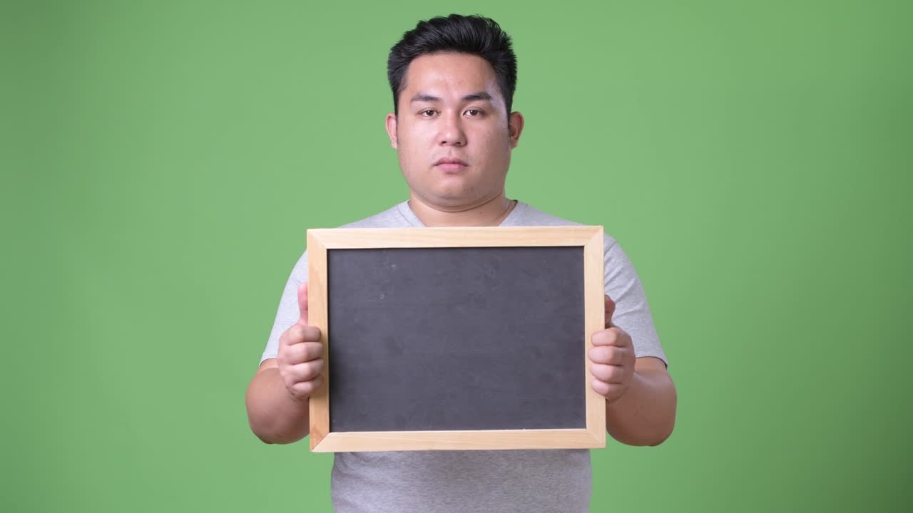 초록색 배경에 젊은 잘생긴 과체중 아시아인