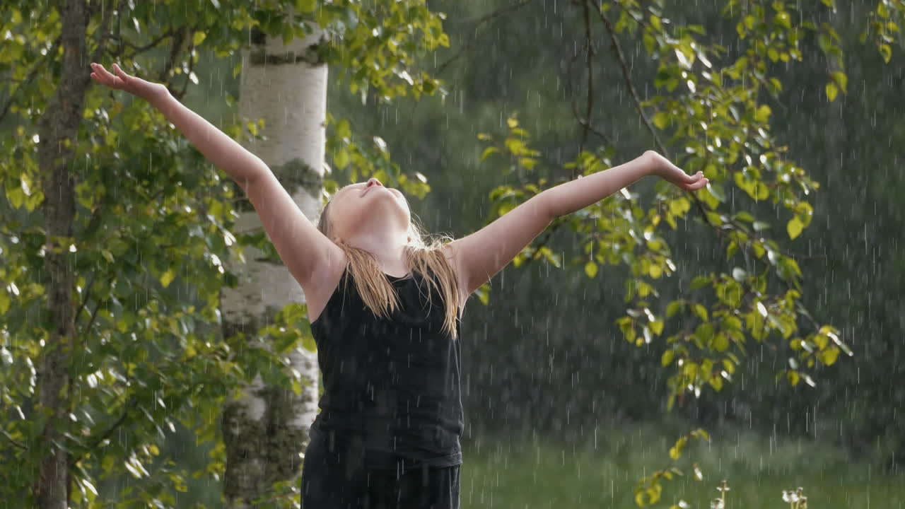 여름 비가 내리는 젊은 금발 소녀가 하늘을 쳐다보며 하나님과 기적을 포옹하고, 느린 동작