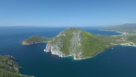 Cinematic-rotating-up-high-4K-drone-clip-over-the-tropical-blue-waters-of-Toroni-in-Chalkidiki-with-some-boats-passing-by