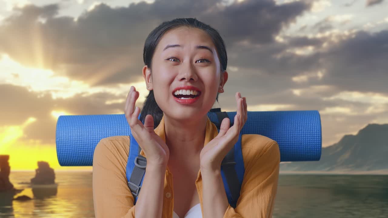 夕焼け時にビーチに立って、登山用バックパックを背負いながら「ワオ」と言うアジア人女性ハイカーのクローズアップ