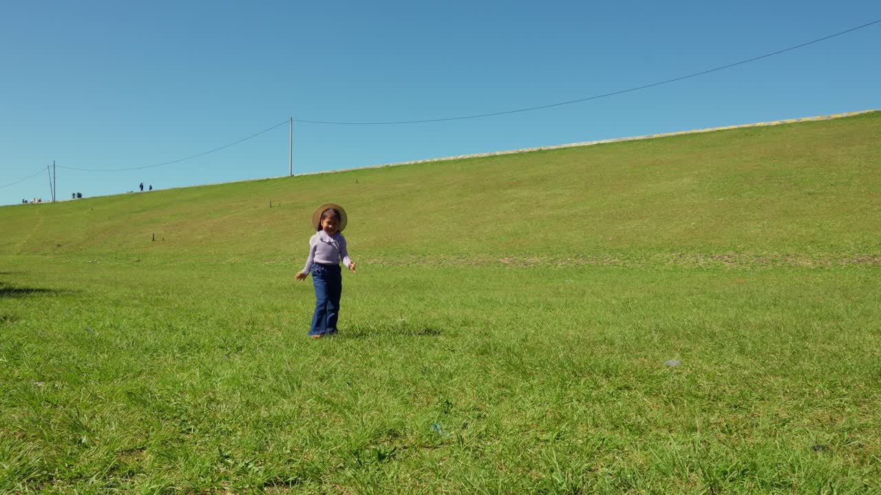 Asian little girl runs and plays on a green hill