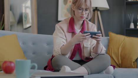 woman playing mobile game on couch