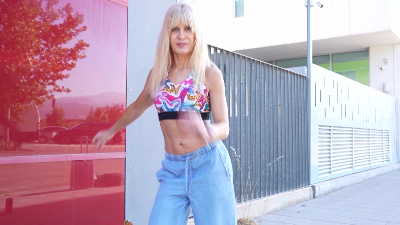 Donna di danza fitness urbana che si muove con abbigliamento casual su uno sfondo urbano colorato