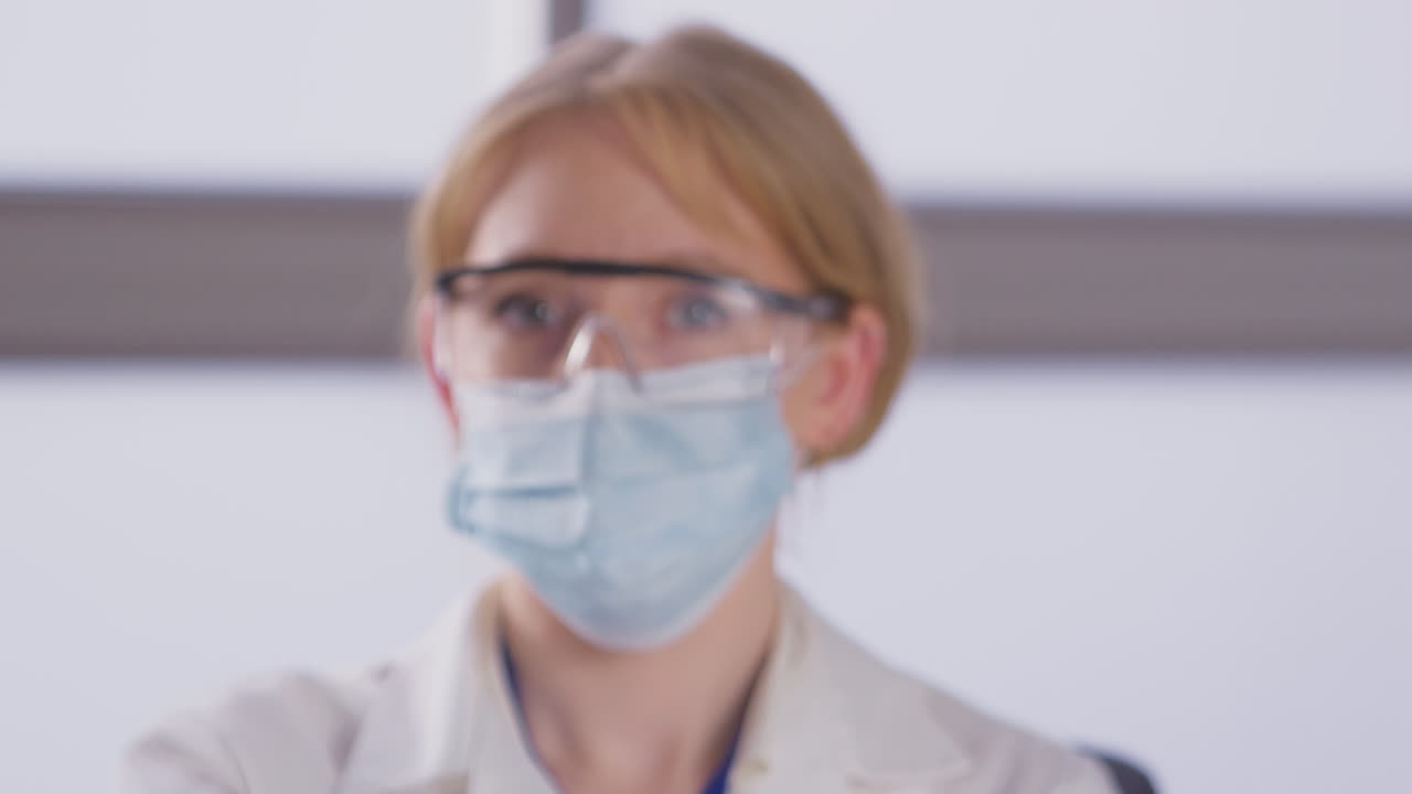 Portrait Of Female Lab Research Worker Wearing PPE Holding Test Tube Labelled Vaccine