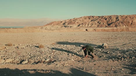 vista ad ampio angolo di un uomo che scava una buca con una pala nell'arido deserto di giudea