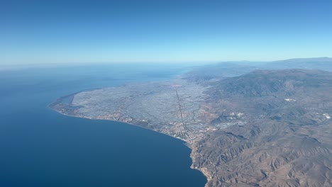 a sea of plastic in el ejido, almeria, the biggest greenhouses area in europe, shot from an airplane cabin in a splendid bright and sunny sky