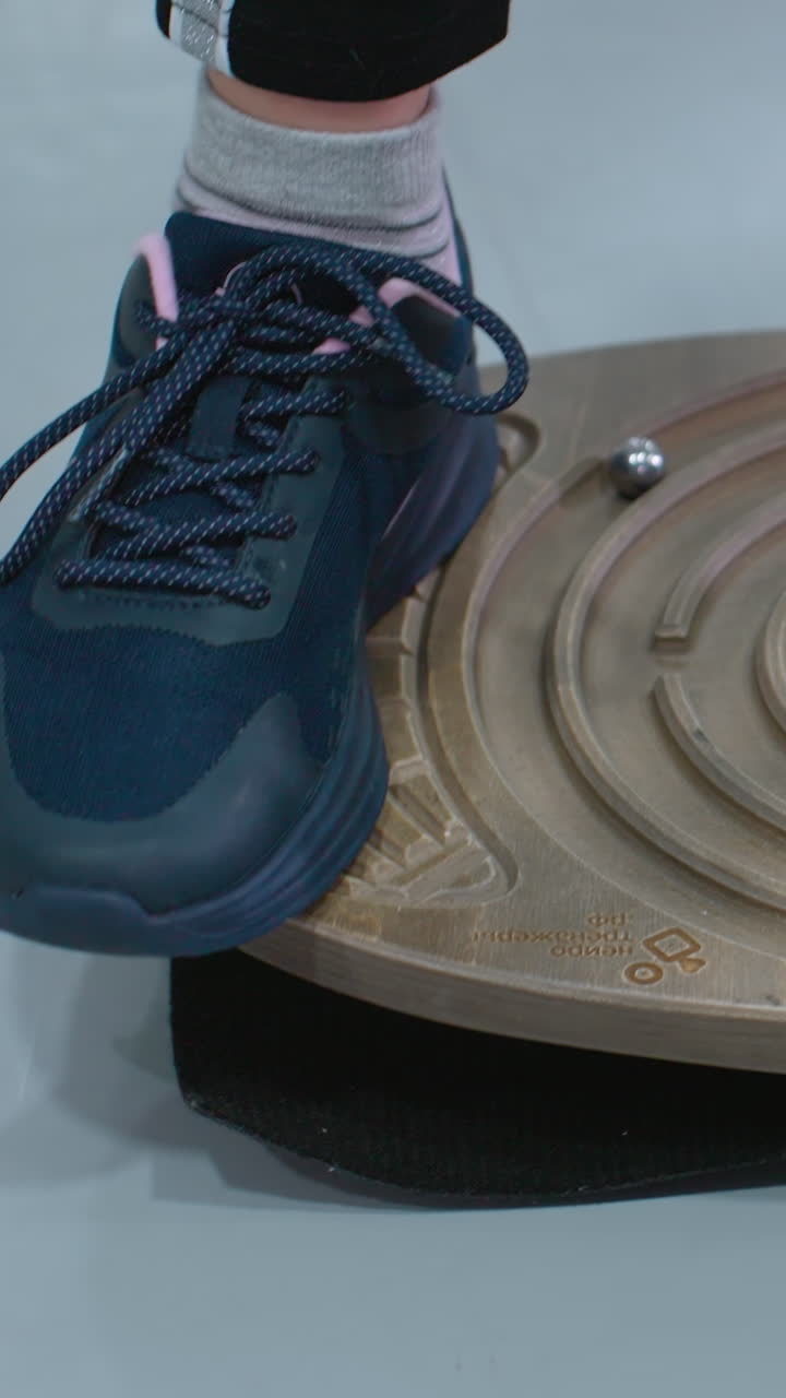 vista de cerca de la pierna de una persona que usa zapatillas de deporte y corredores de pie en una tabla de equilibrio tratando de estabilizarse, el individuo está centrado en mantener el control y el equilibrio