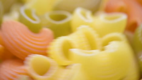 tubo rigate pasta tricolore, macro disparo, tubo rigate pasta tricolore en la mesa girando hacia la derecha