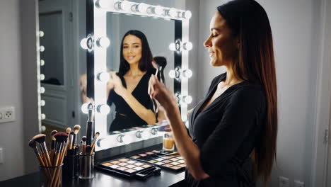 woman applying makeup in front of a vanity mirror