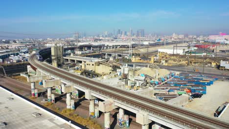 muy buena antena de un tren de cercanías amtrak sobre un puente con el horizonte de los angeles en la distancia