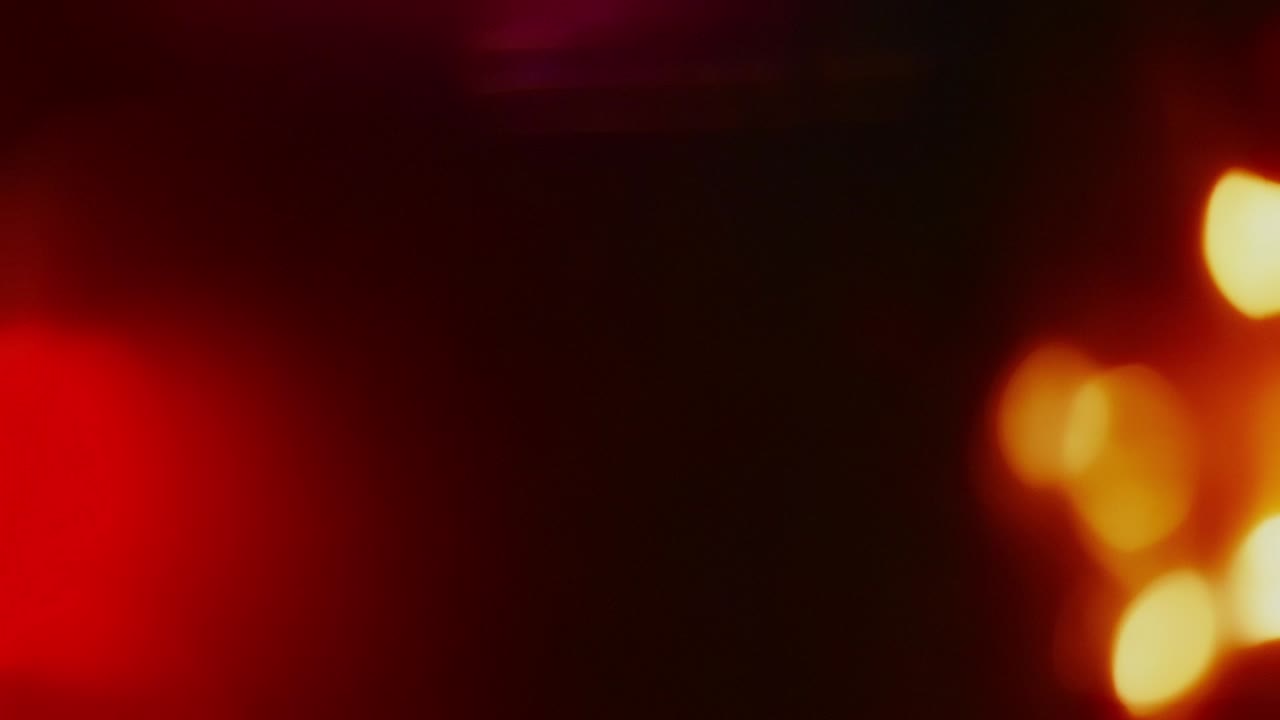 Soft, out-of-focus red and yellow bokeh lights drift and float in a seamless loop. Abstract background or overlay for creating a warm, romantic, or vintage mood. Isolated on black