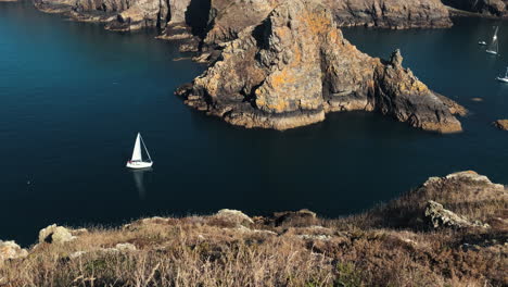 Small-yacht-sails-through-narrow-waterway-towards-sheltered-bay