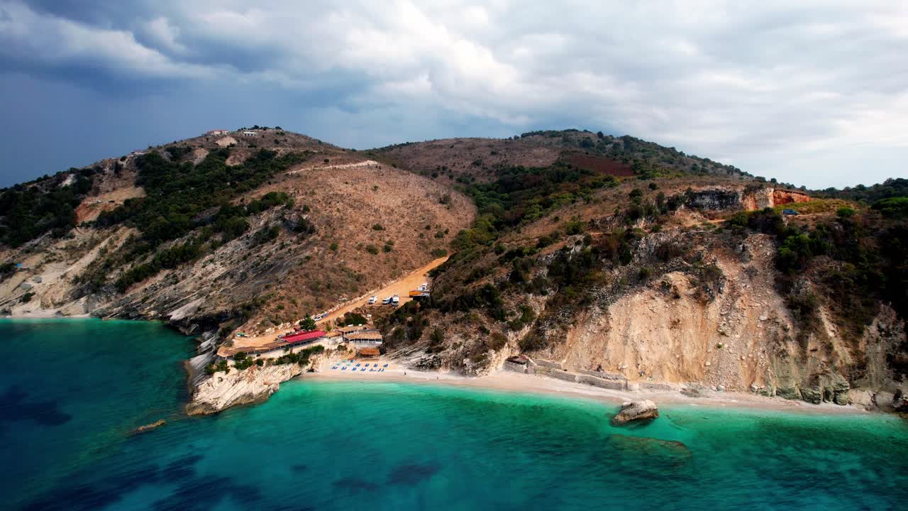 Aerial of Albania coastline, clear sea, sandy beach and mountains.