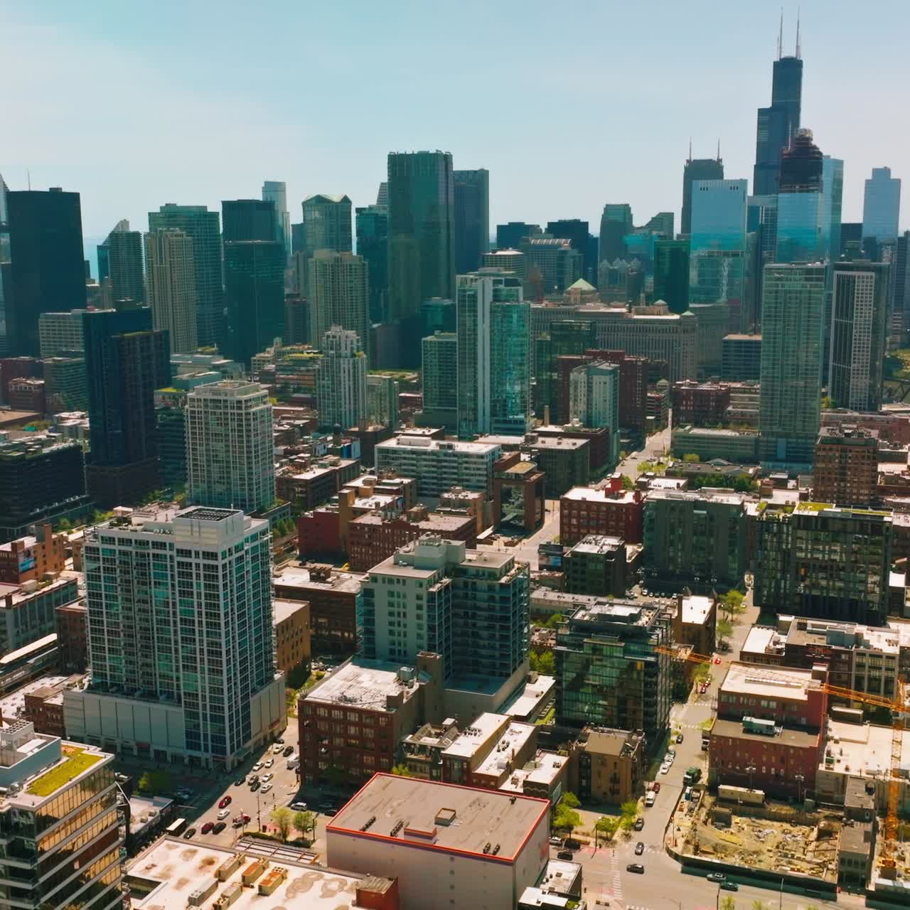 Lively Chicago streets with lots of cars driving by on beautiful sunny day. Dense architecture with amazing skyscrapers at backdrop