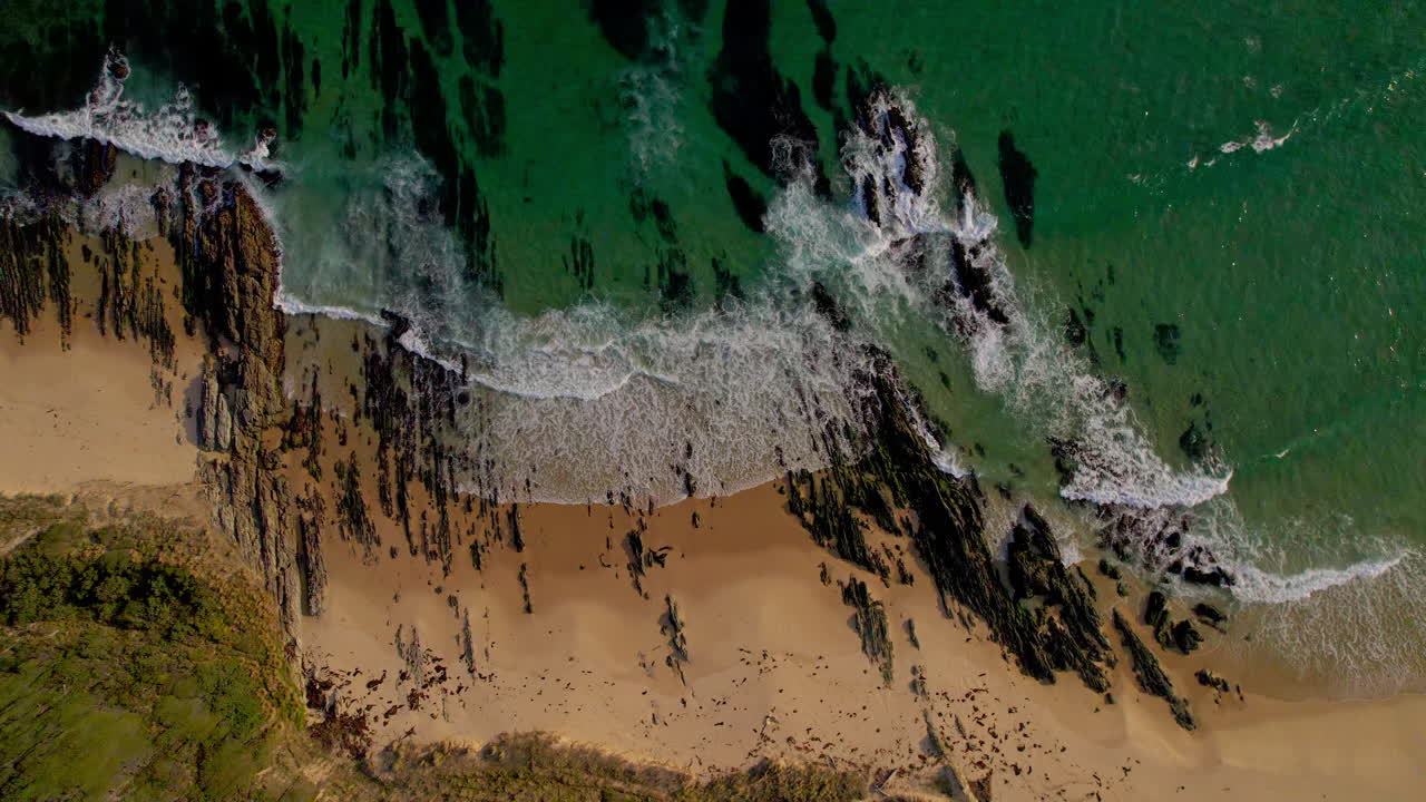 Wide aerial top-down view of Pearl Point in Victoria, showing the remote beach, layered cliffs, and surrounding natural textures from above in stunning detail