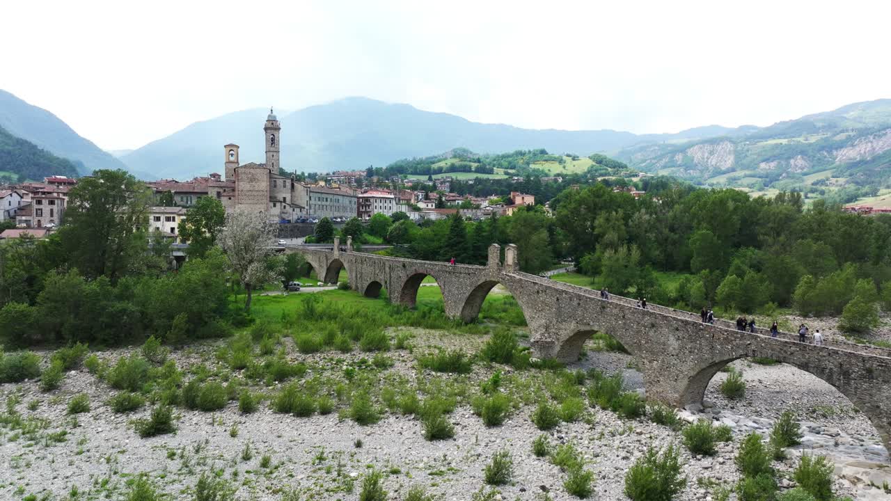 personas caminando a lo largo de ponte gobbo con lecho seco del río, bobbio en italia