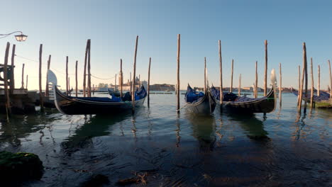 Gondolas-in-a-harbor-in-Venice,-Italy-with-the-sun-rising-in-the-background