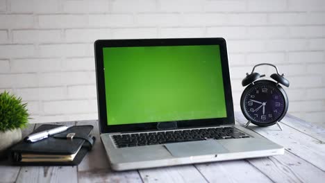 laptop, notebook, and clock on a wooden desk