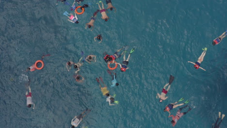 Group-of-snorkelers-swimming-in-a-blue-water-at-the-coral-shoals-observing-underwater-life-with-tourist-boat-adrift-nearby,-Nusa-Penida,-Bali,-Indonesia