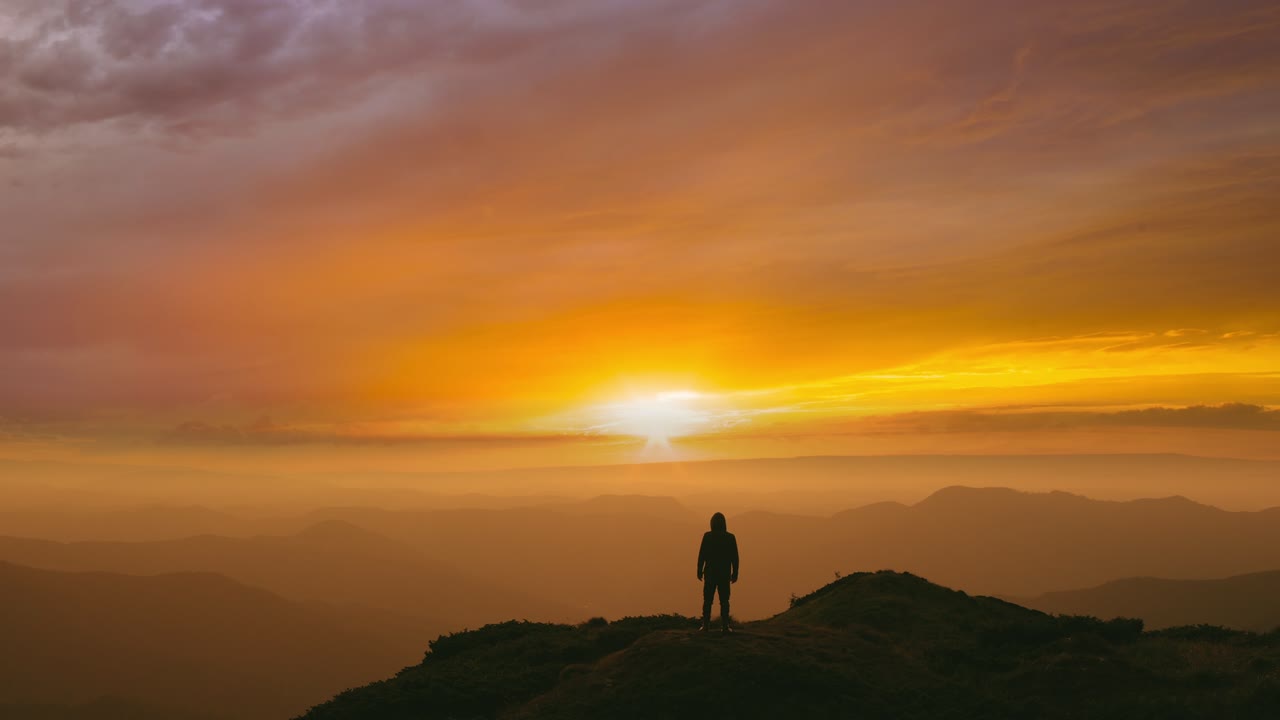 el hombre de pie en la cima de una montaña en el fondo brillante del atardecer