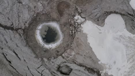 top close shot of flood water start to fill sinkhole with muddy water, dead sea israel, aerial view