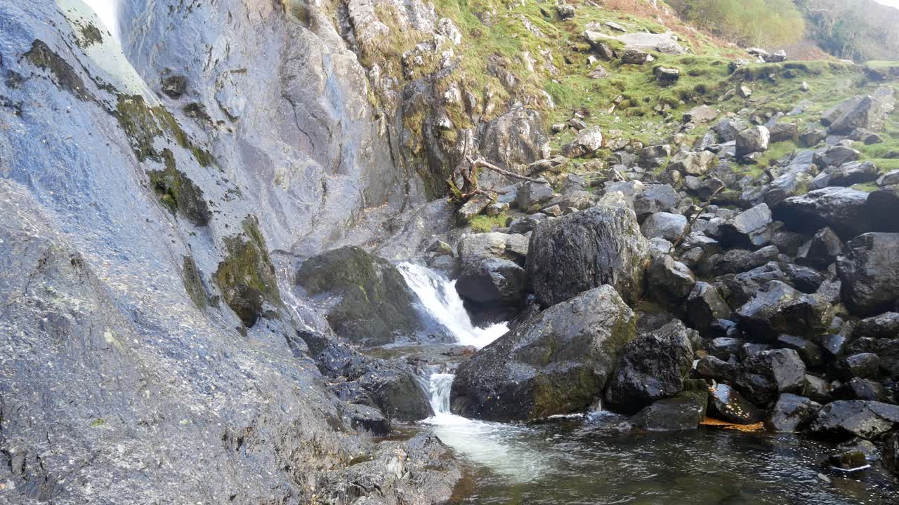 cascada de montaña rocosa que fluye sobre rocas irregulares del río en un valle rural escarpado