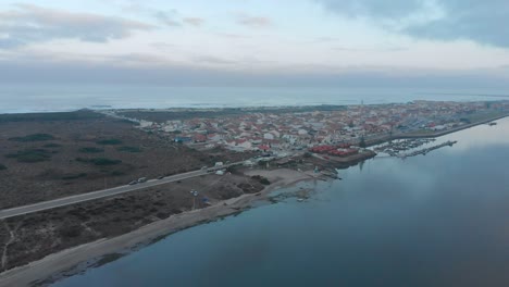 Aerial-view-of-a-small-village-between-the-ocean-and-the-river-on-a-cloudy-day