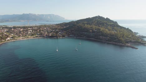 vista aérea de la costa este de cerdeña, drone acercándose a la bahía del mar con velero durante el día soleado de verano